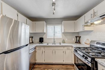 an updated kitchen with white cabinets and stainless steel appliances
